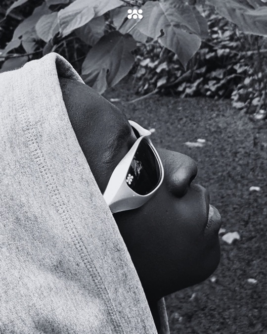 Black and white side profile of a person in a gray hood and Ruvori sunglasses.